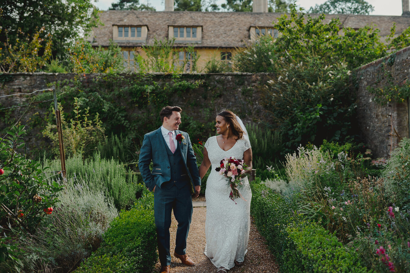 bride and groom walking through gardens at Coombe Lodge by Wiltshire Wedding Photographer Bo Leray